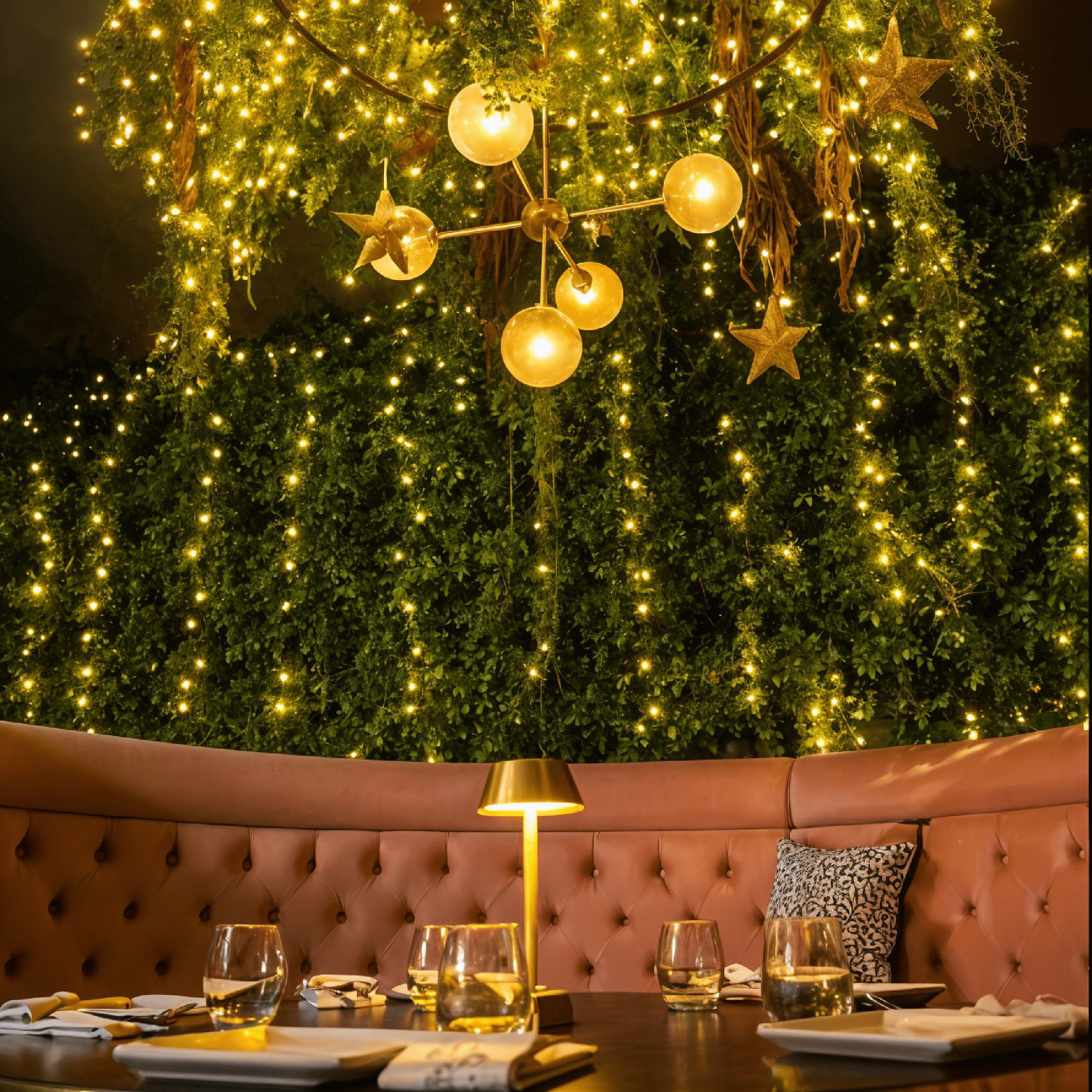 Elegant festive dining area at Shakinah Restaurant in Malta with golden fairy lights, greenery, and a warm, intimate atmosphere.